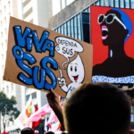a group of people holding up signs in the air — Foto por Tutz Dias na Unsplash
